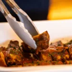Travessa branca com cortes de carne assada lentamente e salpicados de ervas frescas, prato principal do almoco de Dia dos Pais no restaurante Brisa Resto, no Lagune Barra Hotel, na Barra Olimpica