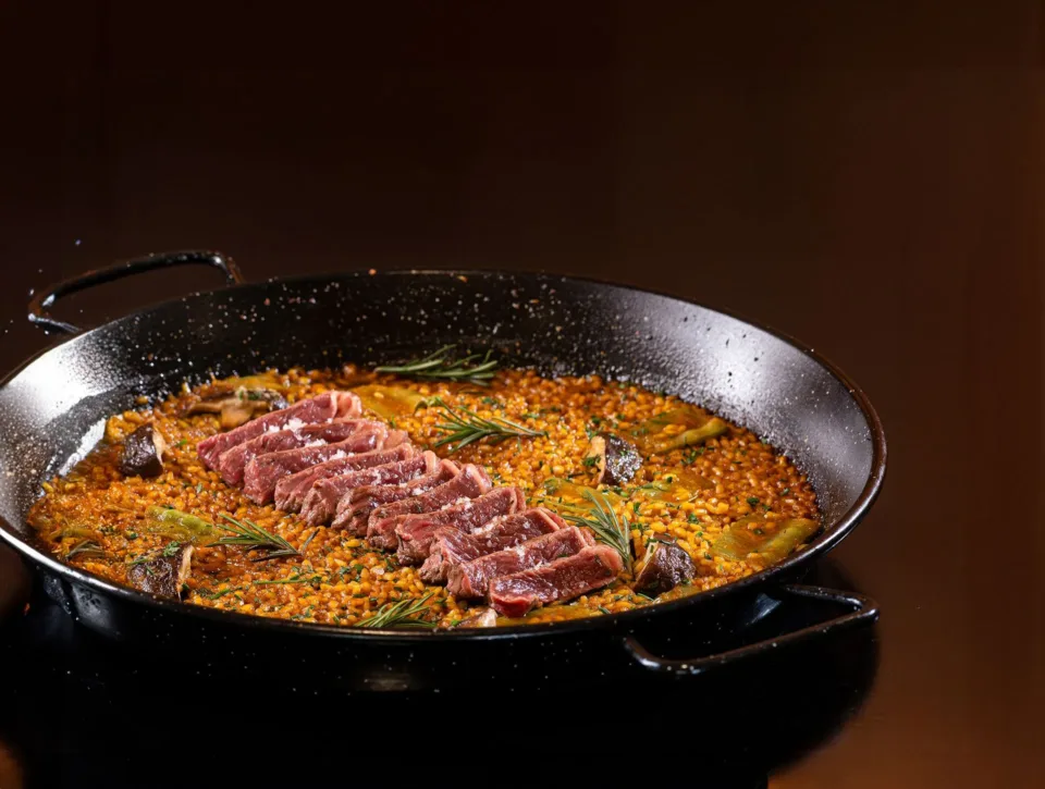 Paella espanhola servida em paellera de ferro, com arroz, legumes e fatias de carne, em restaurante de hotel no Rio de Janeiro