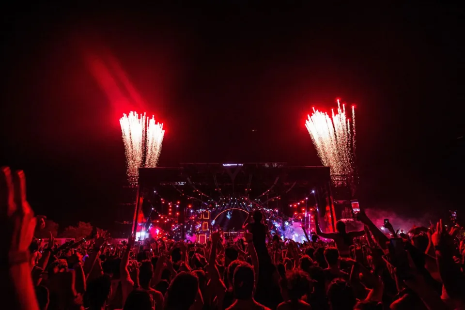 Público com os braços erguidos diante do Palco Mundo iluminado de vermelho, com fogos de artifício, durante o Rock in Rio na Cidade do Rock, no Rio de Janeiro