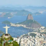 Vista aérea do Cristo Redentor com o Pão de Açúcar e a Baía de Guanabara ao fundo, na cidade do Rio de Janeiro