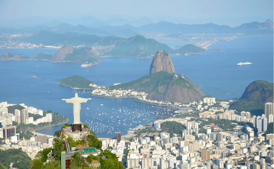 Vista aérea do Cristo Redentor com o Pão de Açúcar e a Baía de Guanabara ao fundo, na cidade do Rio de Janeiro