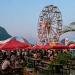 Público circula entre estandes de restaurantes iluminados durante o festival Rio Gastronomia, no Jockey Club Brasileiro, na Gávea, Rio de Janeiro