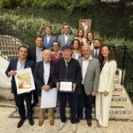 Participantes do Fórum dos Hotéis Cinco Estrelas do HotéisRIO reunidos na escadaria do Santa Teresa MGallery, no Rio de Janeiro, com Nilo Sérgio Félix segurando a placa de homenagem
