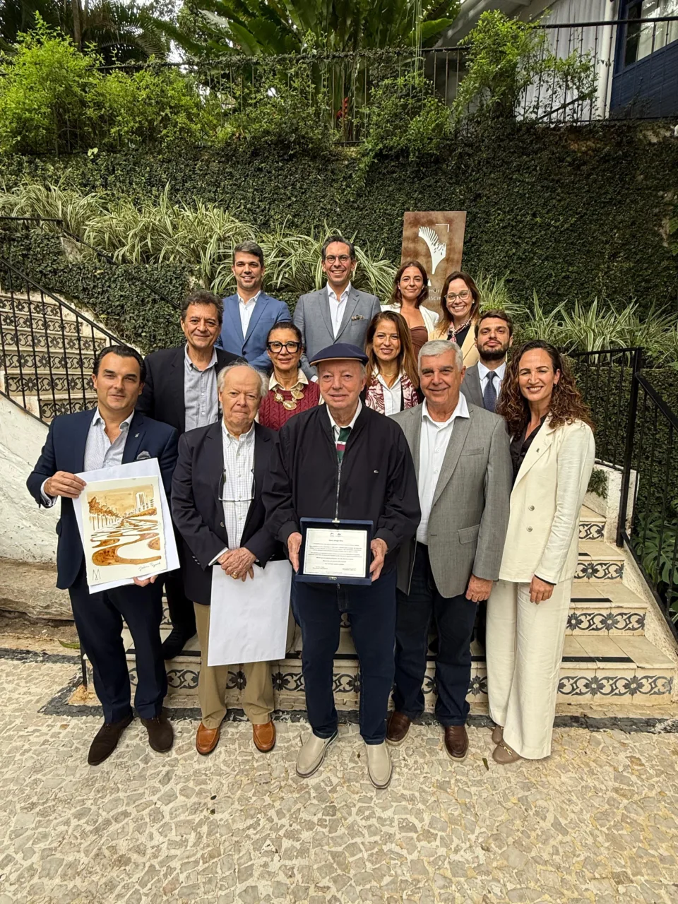 Participantes do Fórum dos Hotéis Cinco Estrelas do HotéisRIO reunidos na escadaria do Santa Teresa MGallery, no Rio de Janeiro, com Nilo Sérgio Félix segurando a placa de homenagem