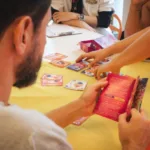 Participantes em mesa de jogos de tabuleiro no encontro Diversidade em Jogo, no Museu de Arte do Rio