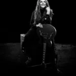 Ana Carolina sentada com guitarra em foto de divulgação da turnê 25 Anas