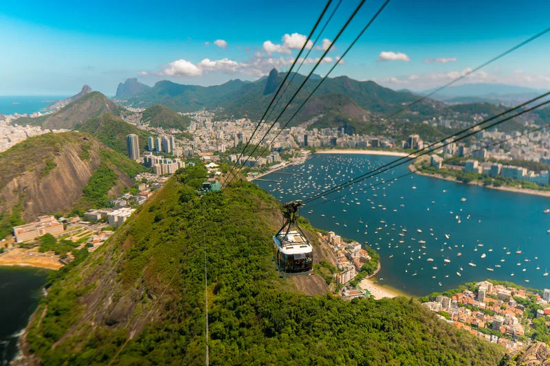Bondinho do Pão de Açúcar em funcionamento com a paisagem da Baía de Guanabara ao fundo