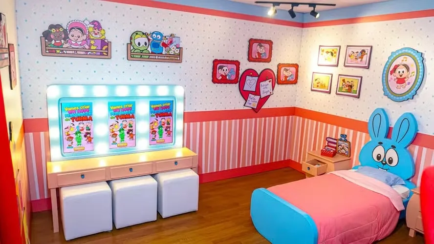 Quarto cenográfico da exposição Casa da Mônica, com cama em formato do coelho Sansão e quadros da Turma da Mônica