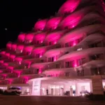 Fachada do CDesign Hotel iluminada de rosa à noite, no Recreio dos Bandeirantes