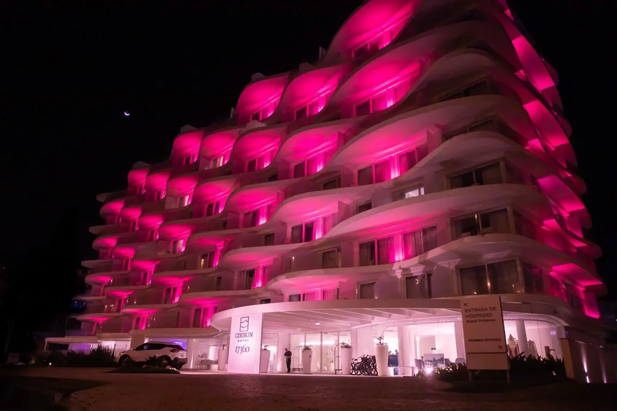 Fachada do CDesign Hotel iluminada de rosa à noite, no Recreio dos Bandeirantes