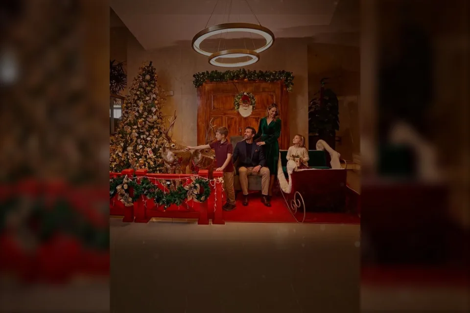 Família ao lado de árvore de Natal, renas decorativas e trenó no Hotel Nacional