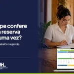 Recepcionista de hotel confere documentos ao lado do computador, em peca da HQBeds em parceria com o HoteisRIO e a ABIH-RJ sobre retrabalho na gestao hoteleira