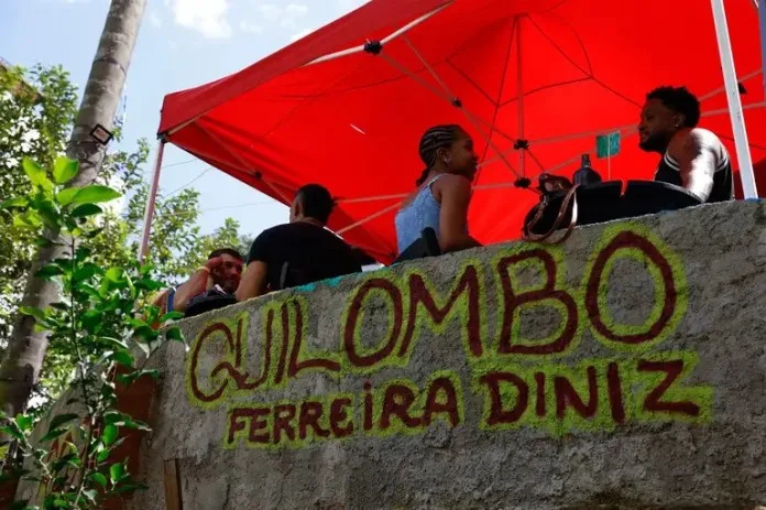 Roda de samba ao ar livre com público reunido em volta dos músicos, no Rio de Janeiro
