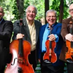 Os quatro músicos do Quarteto Atlas posam ao ar livre com violinos, viola e violoncelo