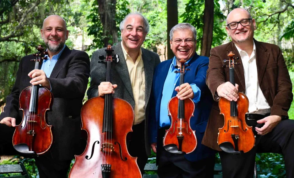 Os quatro músicos do Quarteto Atlas posam ao ar livre com violinos, viola e violoncelo