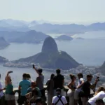 Turistas no mirante do Corcovado com vista para o Pão de Açúcar e a Baía de Guanabara, no Rio de Janeiro