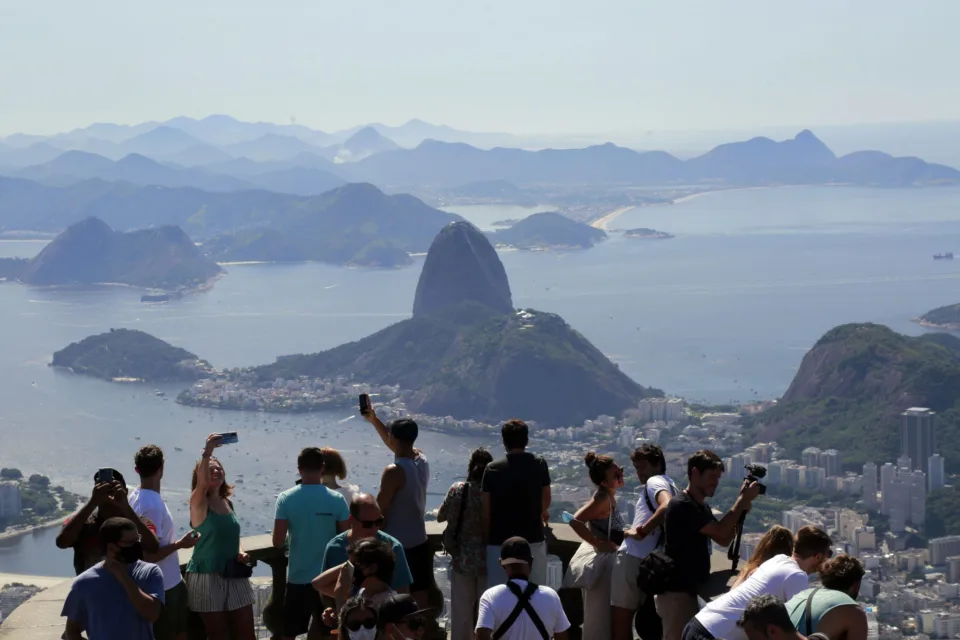 Turistas no mirante do Corcovado com vista para o Pão de Açúcar e a Baía de Guanabara, no Rio de Janeiro