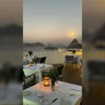 Mesa posta ao ar livre no Vila Santa Teresa ao entardecer, com o Pão de Açúcar ao fundo, no Rio de Janeiro