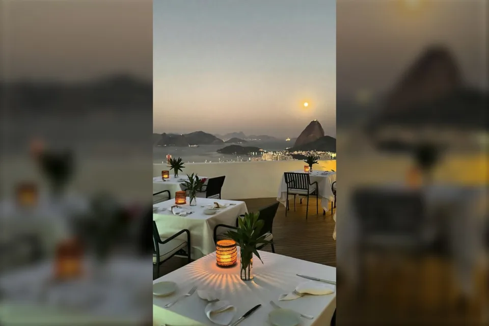 Mesa posta ao ar livre no Vila Santa Teresa ao entardecer, com o Pão de Açúcar ao fundo, no Rio de Janeiro